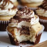 Homemade tiramisu cupcakes with mascarpone frosting and cocoa dusting, bitten to reveal a soft, coffee-soaked center.