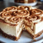 Homemade cinnamon roll honeybun cheesecake with a thick graham cracker crust, creamy filling, cinnamon swirl frosting on top, and a gooey cinnamon-sugar layer inside. One slice is cut to show the rich, layered texture.