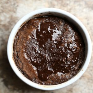 Freshly baked chocolate pudding cake in a white ramekin, with a glossy, molten center and a soft, risen top.