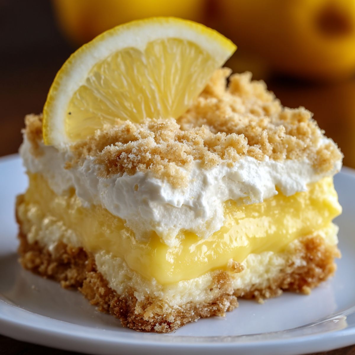 Homemade lemon cream cheese dump cake with layers of creamy filling, lemon pudding, whipped topping, and a crumbly crust, topped with a lemon slice.