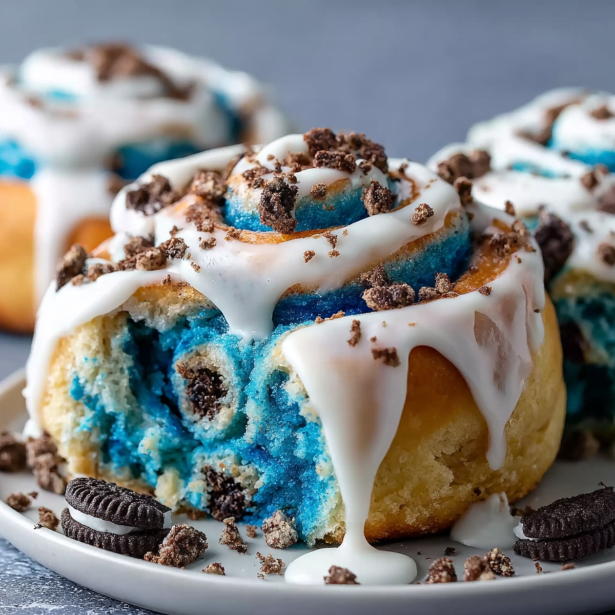 Easy Cookie Monster Cinnamon Rolls with blue swirled dough, white icing drizzle, Oreo crumbles, and golden edges.