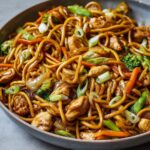 Chicken Lo Mein Recipe in a skillet with glossy noodles, tender chicken pieces, broccoli florets, carrots, onions, and scallions tossed in a rich soy-based sauce — perfectly caramelized and ready to serve, showing real home-cooked texture and freshness.