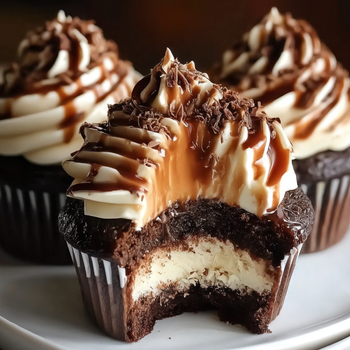 Homemade chocolate coffee cream cupcakes with rich espresso frosting, chocolate drizzle, and a creamy filling inside, shown close-up on a plate.