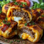 Garlic Butter Bacon Cheeseburger Rollups with golden, flaky crust, gooey melted cheese, and juicy beef filling, topped with crispy bacon pieces and fresh parsley on a wooden board.