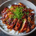 Homemade teriyaki chicken served over steamed white rice, glazed with a glossy soy-ginger sauce and topped with sesame seeds and sliced green onions.
