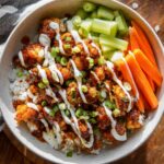 Homemade Buffalo Chicken Bowls with ranch drizzle, green onions, celery, and carrots.