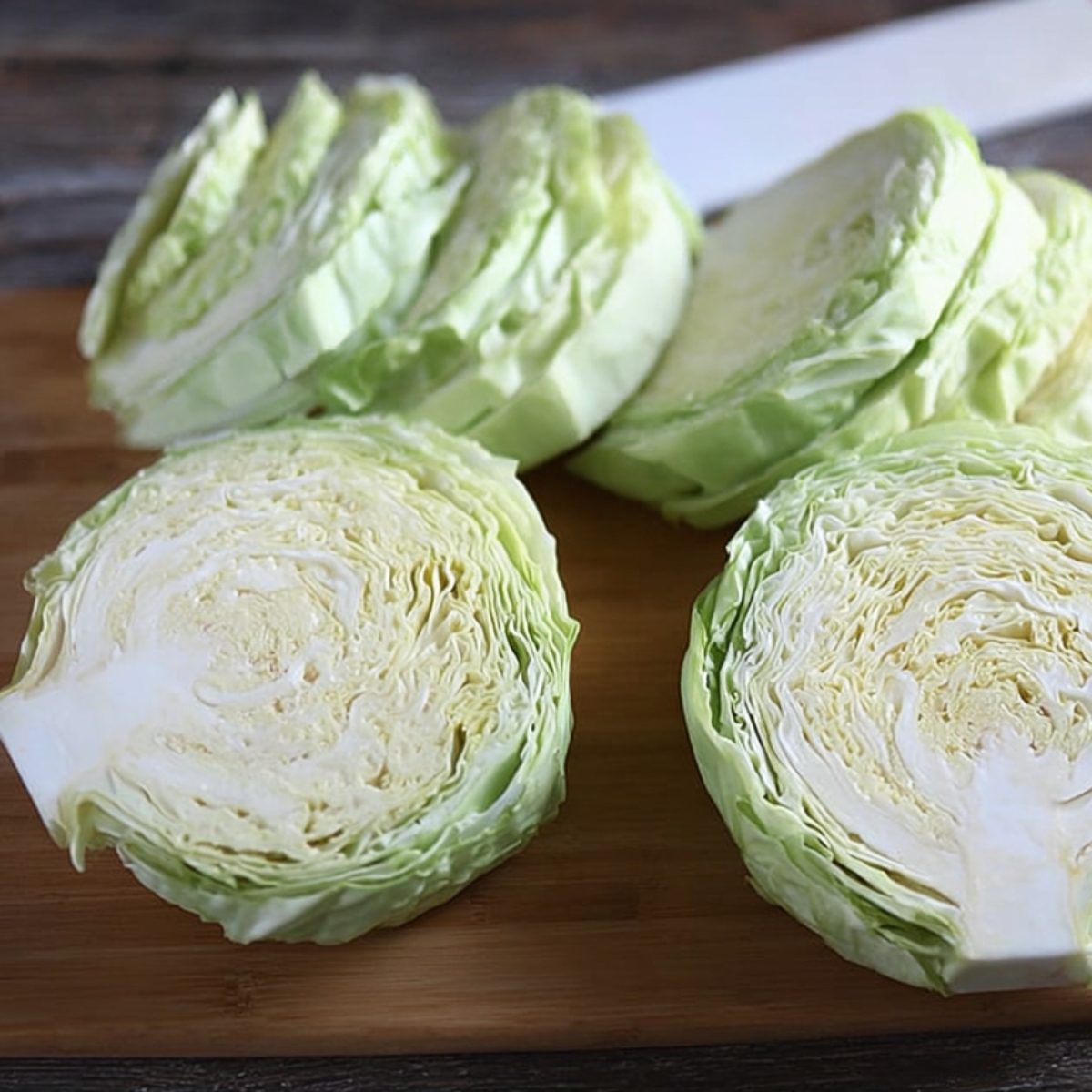 Start by cutting the stems off your cabbage heads. Then cut each one in half through the core. Take each half and cut it into two more thick slices. You want them about ¾ to 1 inch thick—sturdy enough to hold together but not so thick they won't cook through. You should end up with four nice cabbage steak pieces per head.