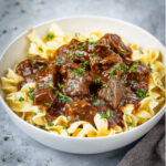 Tender Beef and Noodles covered in thick brown gravy, garnished with parsley
