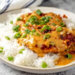 Chicken Diablo with creamy sauce, topped with chopped green onions, served over a bed of white rice.