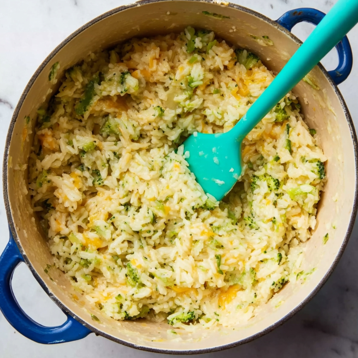 A pot of rice with melted cheese and broccoli, ready to be shaped into rice balls.