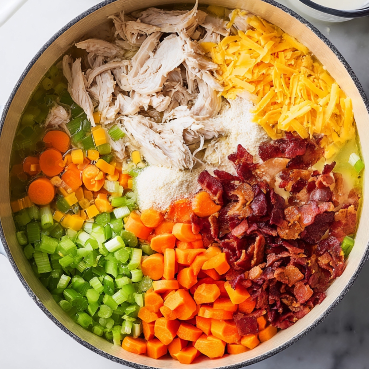 In a large Dutch oven, add the chopped chicken, condensed chicken soup, chicken broth, milk, softened cream cheese, celery, carrots, ranch seasoning mix, and crumbled bacon. Stir everything together so the cream cheese starts to break down and blend into the liquid.
