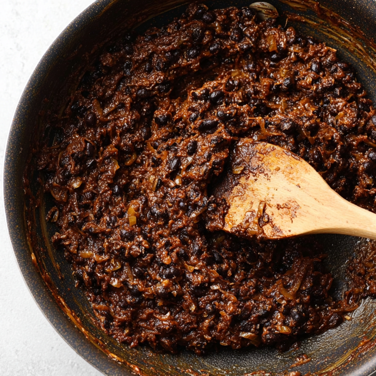 Onion and black bean mixture cooking in a pan.