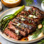 Juicy grilled Steak Marinade served with roasted asparagus, garlic, and fresh herbs, topped with melted butter for extra flavor.