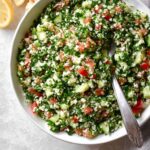 The final mixed Cauliflower Tabbouleh, with a blend of cauliflower rice, tomatoes, cucumbers, green onions, and parsley, ready to be served.