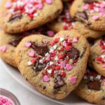 Heart Shaped Chocolate Chip Cookies decorated with pink, red, and white sprinkles, featuring gooey chocolate chunks.