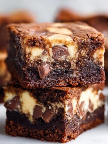 Stacked chocolate chip Banana Bread Brownies with rich fudgy layers and creamy swirl texture on a white surface.
