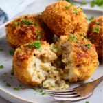 Golden-brown Chicken Croquettes with a crispy crust, some cut open to reveal the creamy filling inside, garnished with parsley.