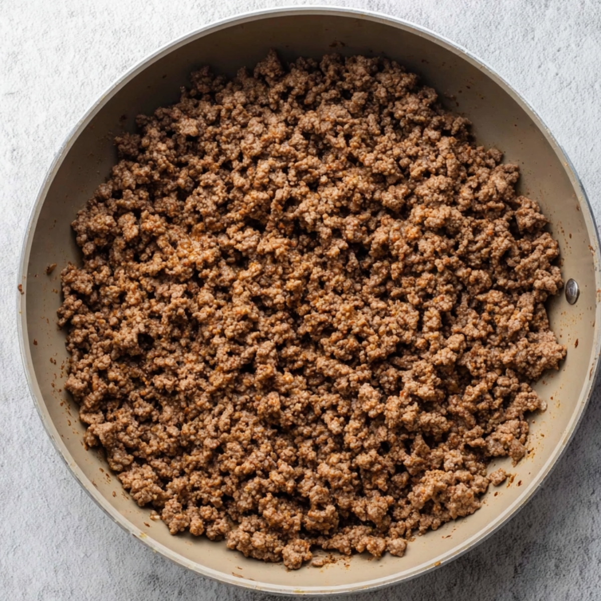 Cooked ground beef in a pan, showing a rich, browned texture, ready to be used in a variety of dishes like sloppy joe casserole or other hearty meals.