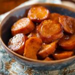 A bowl of tender, glazed Southern Candied Yams served with a rich syrup.