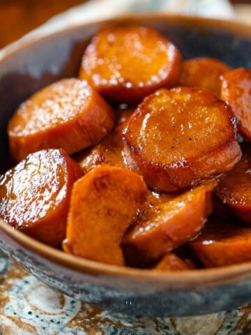 A bowl of tender, glazed Southern Candied Yams served with a rich syrup.